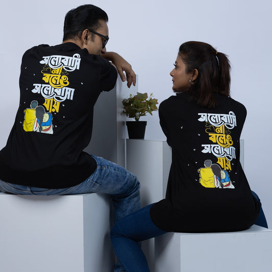Couple wearing matching 'Bhalobasi Na Boleo' oversized Bengali T-shirts, showcasing a stylish and cultural design.