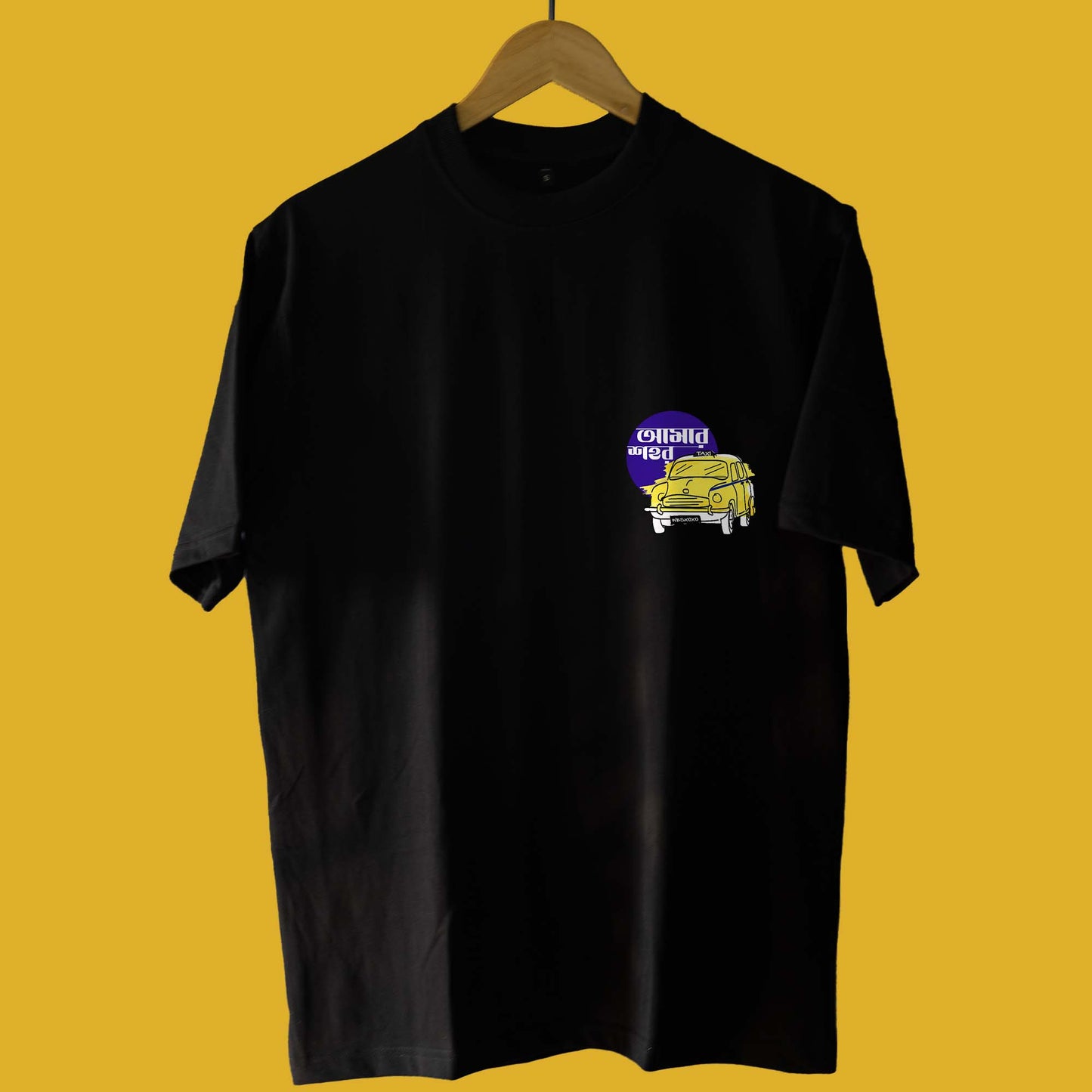 Front view of Eso Amar Shohore Kolkata T-Shirt with a minimalist yellow taxi graphic and Bengali text on a black oversized unisex fit.