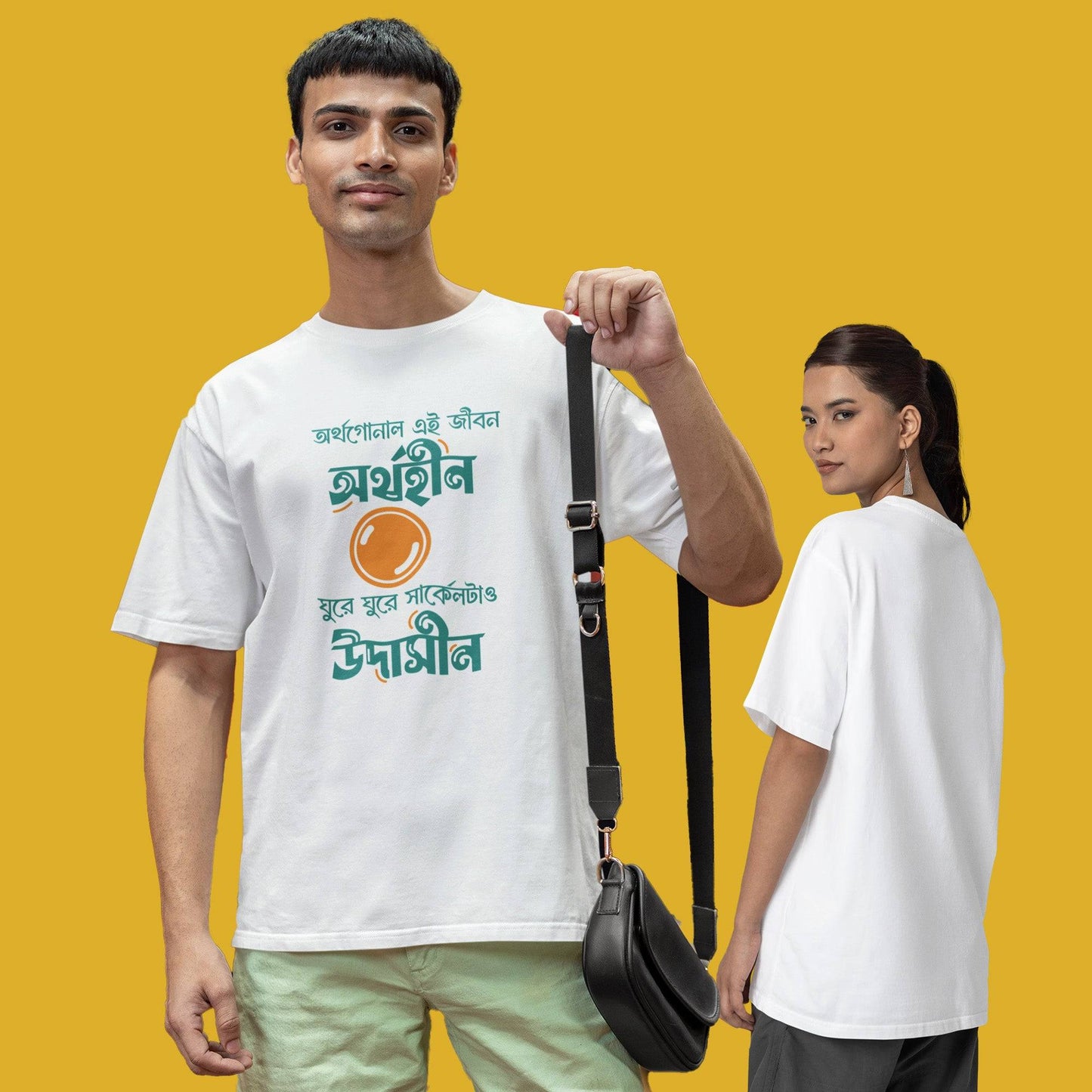 White oversized unisex T-shirt with funny Bengali typography caption, modeled by a man and woman against a yellow background.