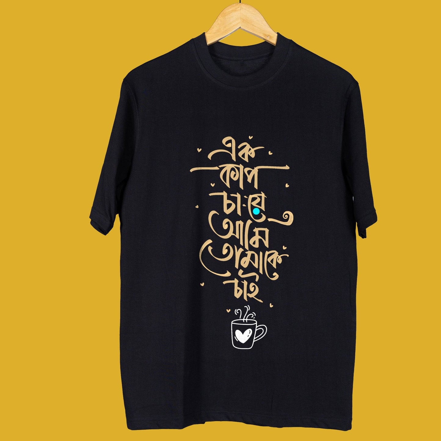 Black oversized unisex T-shirt with Bengali quote 'Tomake Chai' in artistic typography, featuring a coffee cup graphic, displayed on a hanger.