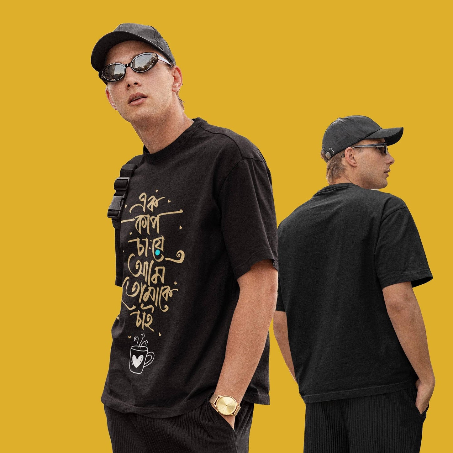 Model wearing black oversized unisex T-shirt with Bengali quote 'Tomake Chai,' styled with sunglasses and cap, showcasing front and back views.