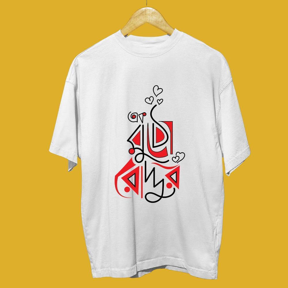 White oversized t-shirt with red-accented Bengali typography and heart design, displayed on a wooden hanger.
