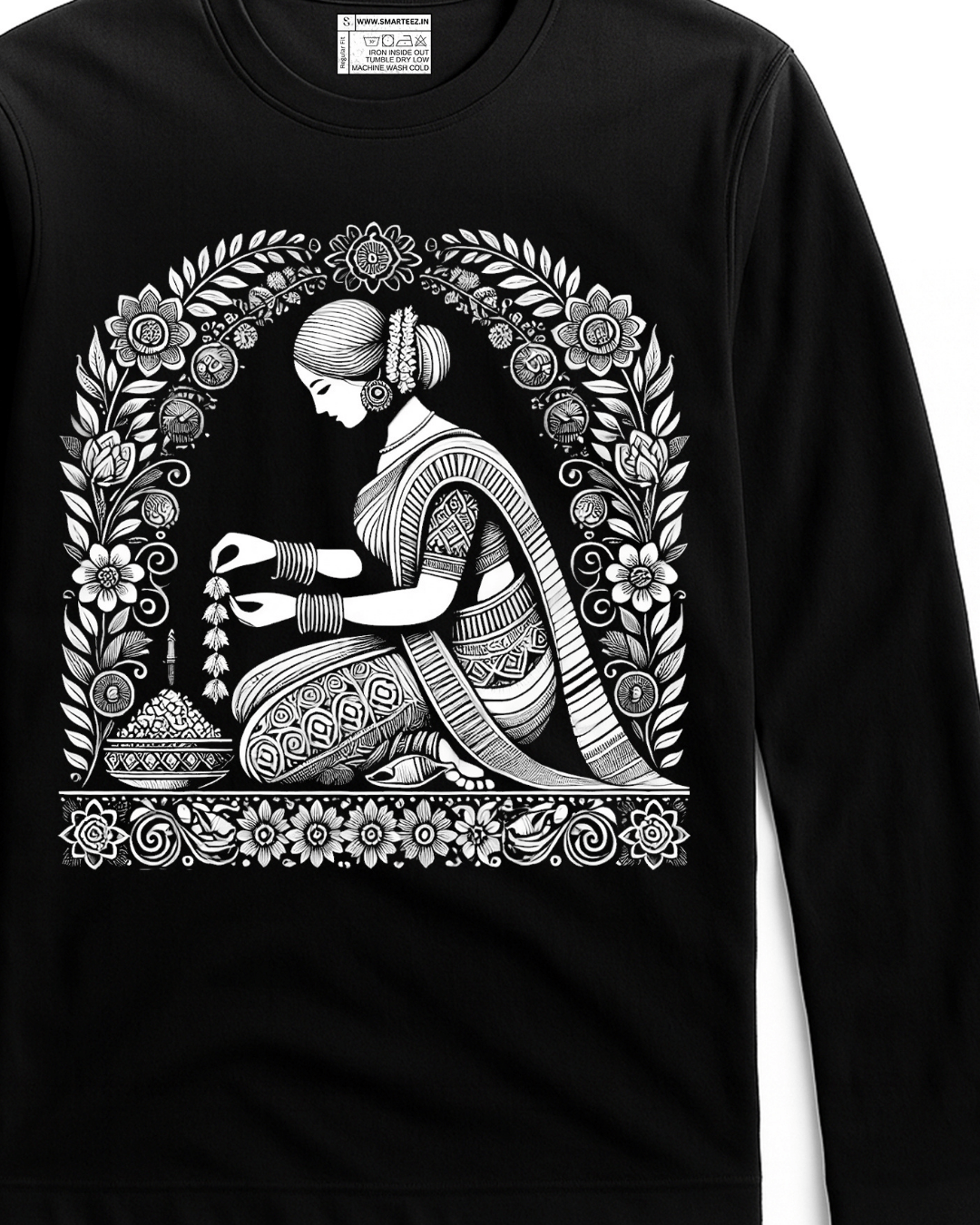 Malini Alpona Art T-shirt features intricate Bengali folk art of a woman creating Alpona, printed in white on a black full sleeves cotton tee. Unisex fit ideal for cultural fashion lovers.