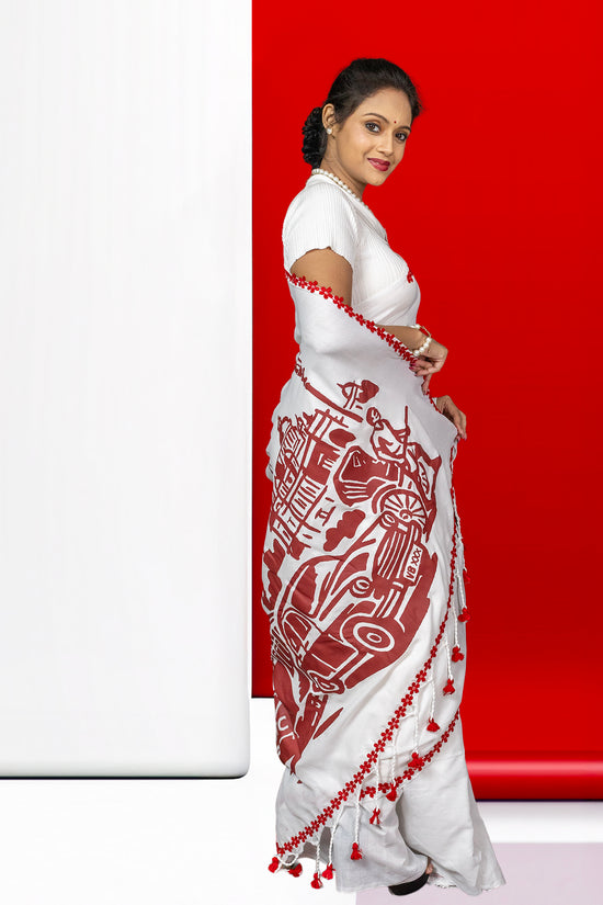 Traditional cotton saree with Kolkata cityscape print, including tram and vintage car, bordered with red tassels for festive elegance.