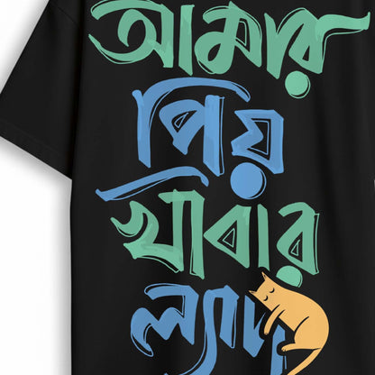 Close-up of black 'Amar Priyo Khabar Lyadh' Oversized Bengali Graphic T-shirt showcasing vibrant text and a playful cat graphic.