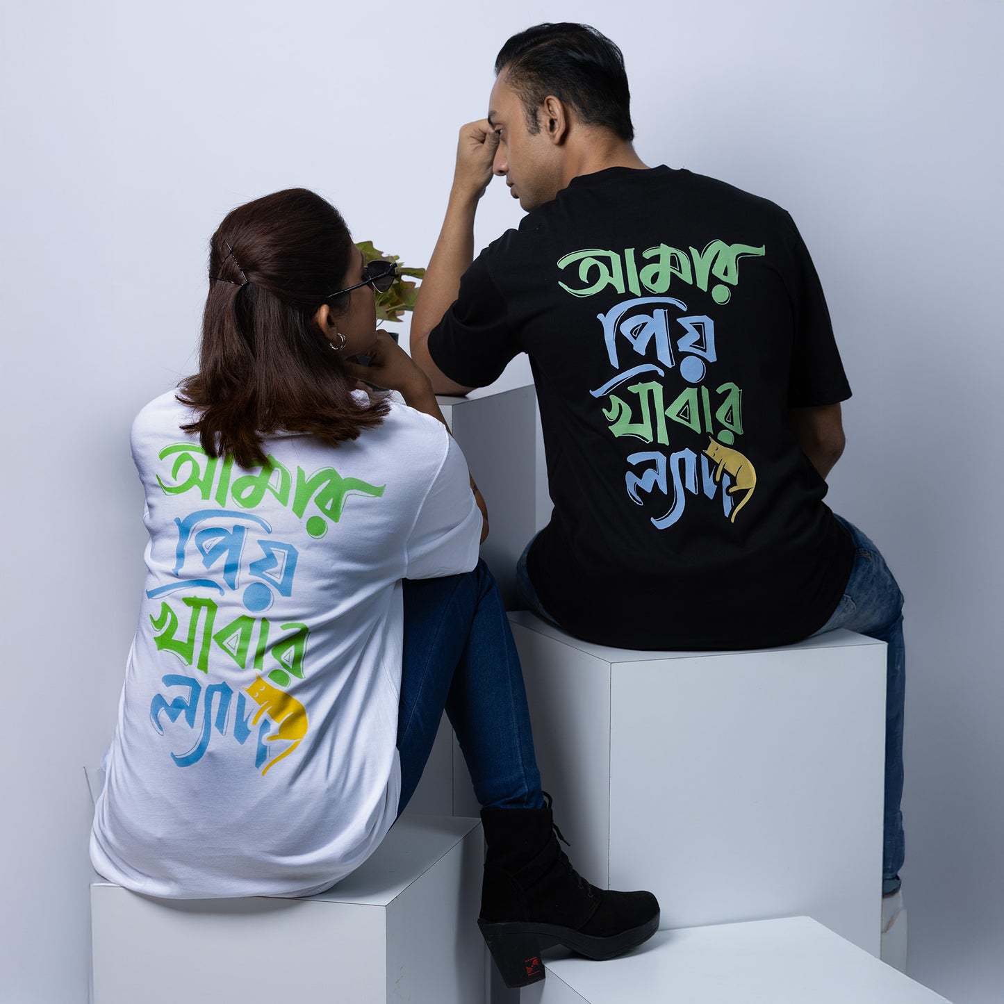 Couple wearing black and white 'Amar Priyo Khabar Lyadh' oversized Bengali T-shirts, perfect for Gen Z casual streetwear style.