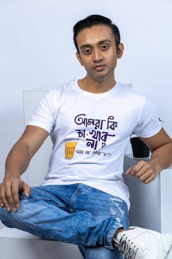 Man wearing a white unisex Bengali funny T-shirt with 'Amra Ki Cha Khabo Na' slogan and tea cup graphic, paired with blue jeans in a casual setting.