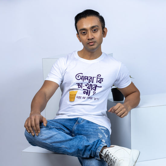 Man wearing a white unisex Bengali funny T-shirt with 'Amra Ki Cha Khabo Na' slogan and tea cup graphic, paired with blue jeans in a casual setting.