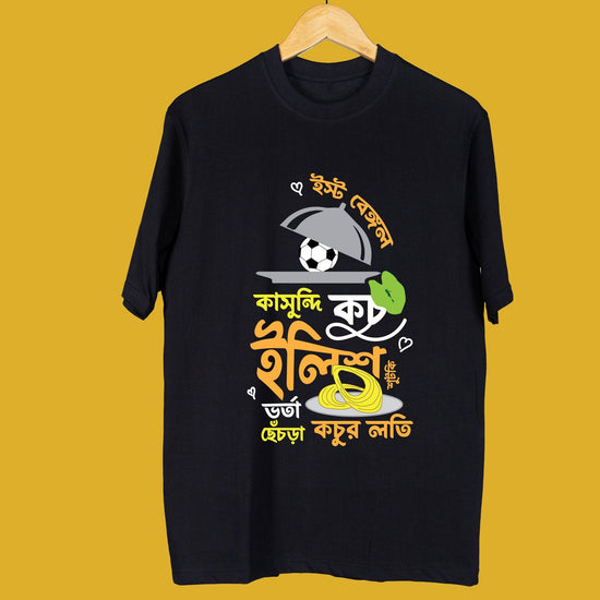 Black Bangal-kahini oversized unisex T-shirt displayed on a hanger, featuring vibrant Bengali typography and playful graphic design.