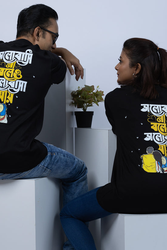 Couple wearing matching 'Bhalobasi Na Boleo' oversized Bengali T-shirts, showcasing a stylish and cultural design.