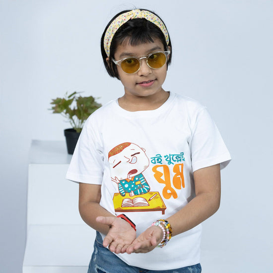 Buy Bengali TShirt for Kids - 'Boi Khulle i Ghum' Funny Bengali TShirt. Soft cotton white T-shirt featuring a cute cartoon of a sleepy child with books.