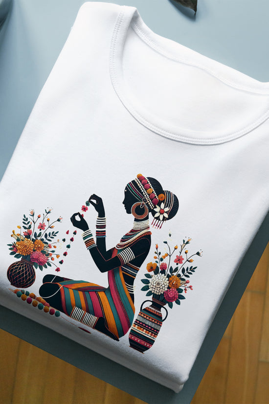 Chayanika Graphic Tee - Folk Art T-Shirt featuring a tribal woman with floral garlands on premium cotton, folded neatly on a table.
