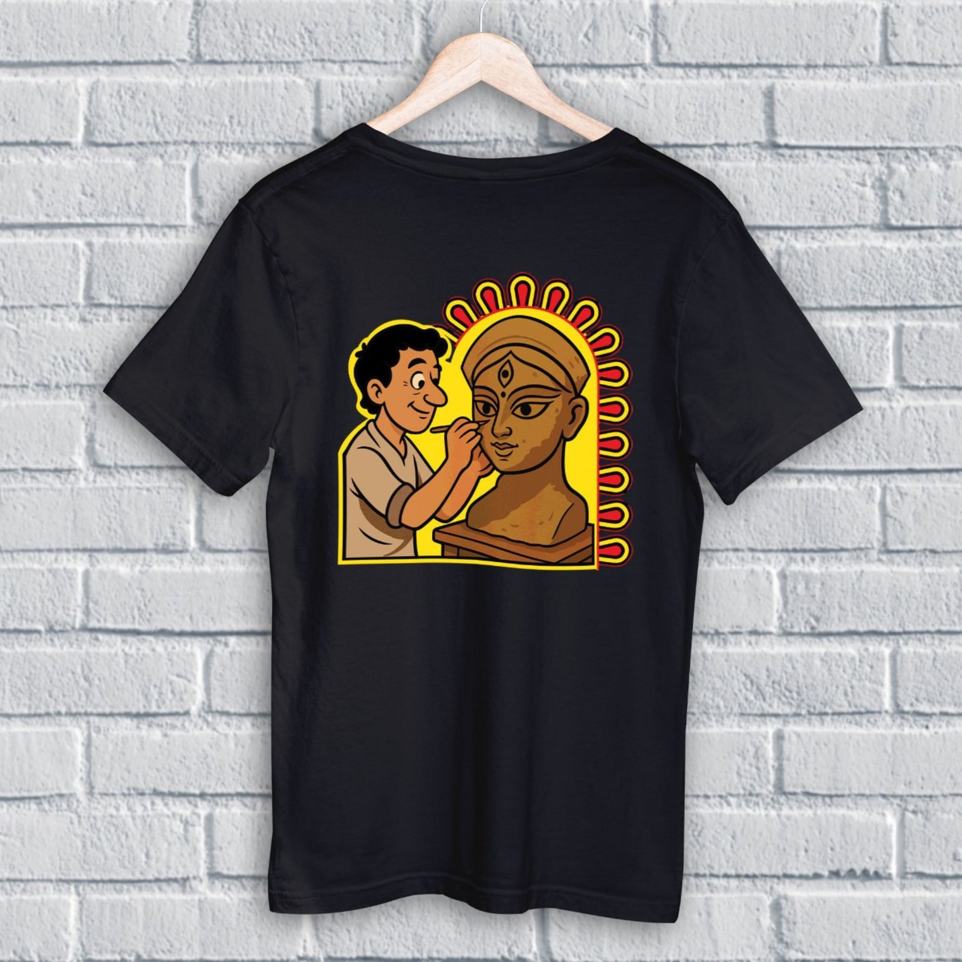 Durga Puja T-Shirt - Artistic Tribute | Premium Cotton, Unisex, featuring cartoon-style idol maker painting Maa Durga on black fabric.
