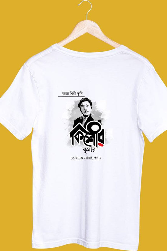 White unisex T-shirt featuring a Kishore Kumar graphic design in Bengali script, displayed on a hanger against a yellow background.