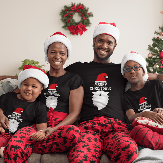 Family wearing matching Merry Christmas Santa T-shirts with festive Santa hat and beard design, sitting on a couch with holiday decor.