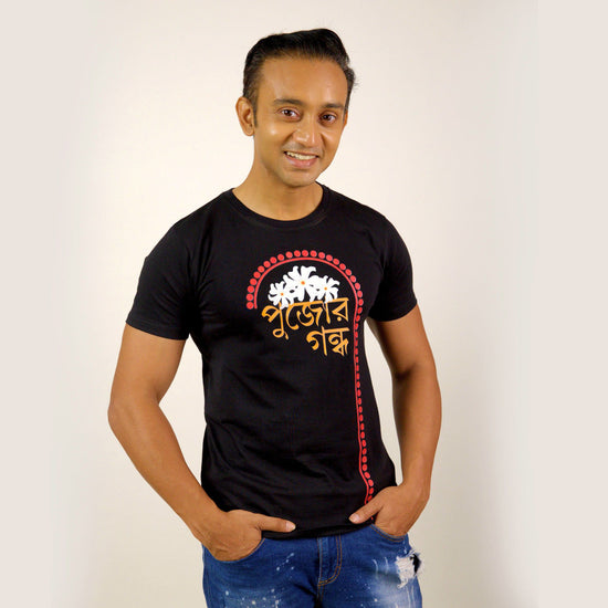 Durga Puja T-Shirt - Pujor Gondho in black with Bengali typography and sheuli flower design, unisex regular fit for festive wear.