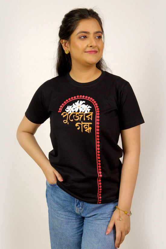 Durga Puja T-Shirt - Pujor Gondho in black with sheuli flower design and Bengali typography, unisex regular fit for festive wear.