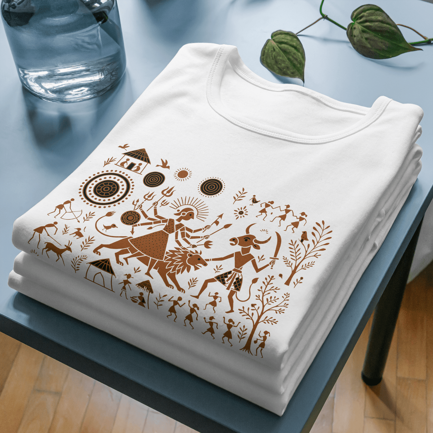 Durga T-Shirt - Warli Art Mahishasura design in brown on folded white cotton unisex tee, showcasing spiritual and cultural heritage.