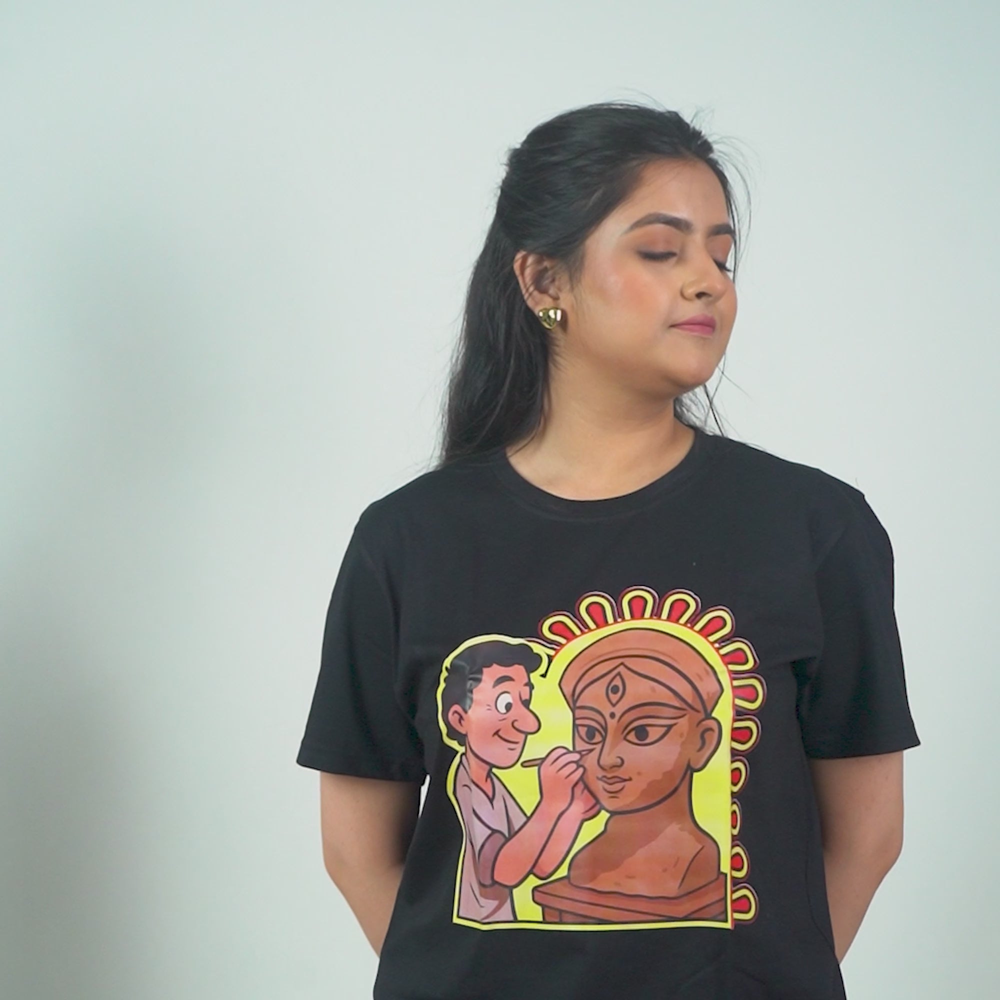 Durga Puja T-Shirt featuring cartoon-style idol maker sculpting Goddess Durga, printed on premium black cotton, unisex regular fit design.