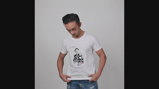 Model showcasing a white unisex T-shirt with a Kishore Kumar graphic design in Bengali script, paired with casual denim jeans.